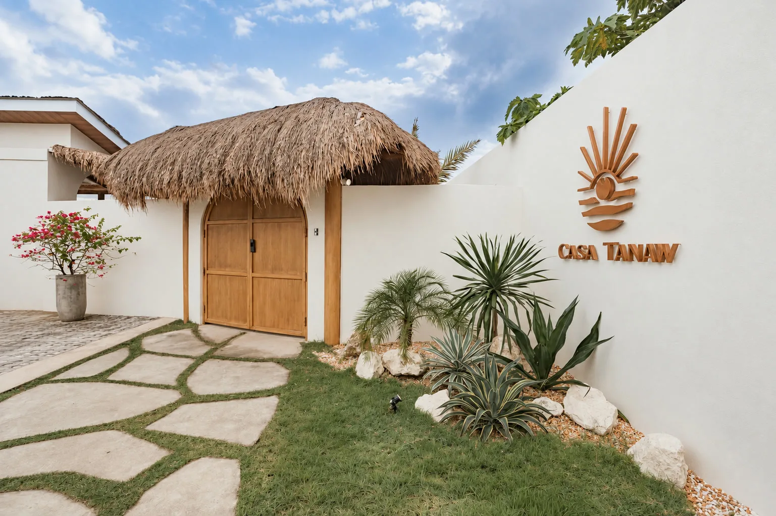 Casa Tanaw entrance garden with tropical plants, white stones, and an organic stepping-stone path