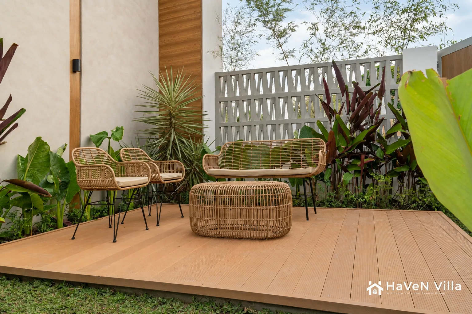 Rattan lounge furniture on a timber deck surrounded by tropical foliage