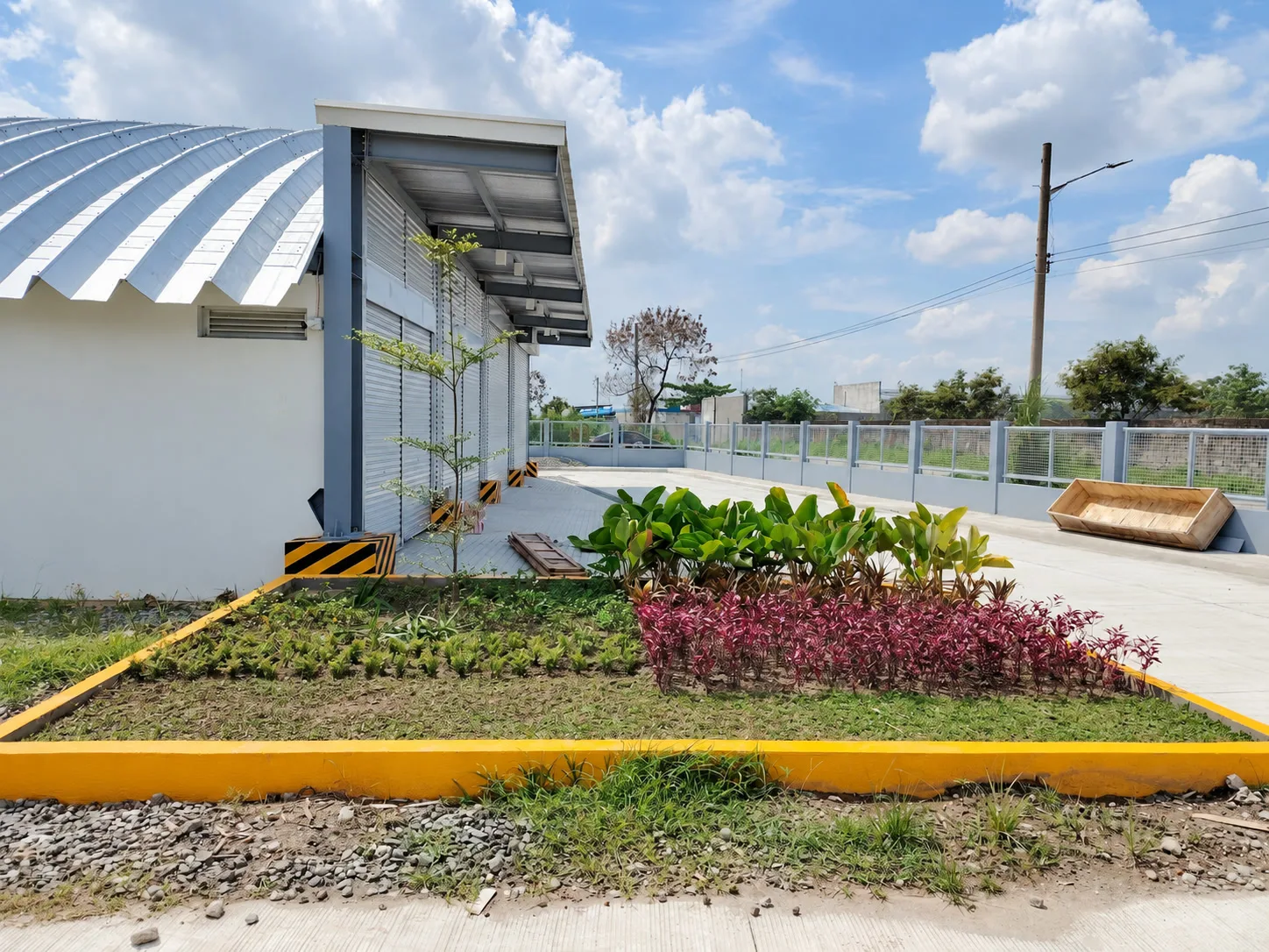 Green and burgundy planting in a yellow-edged bed beside the service building